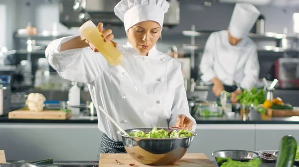 En un famoso restaurante Mujer cocinera prepara ensalada, anuncios de aceite. Ella... —  Fotos de Stock