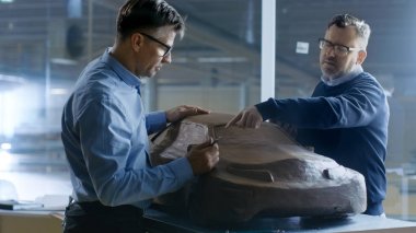 Two Male Automotive Designers Working on a Clay Model of New Gen clipart