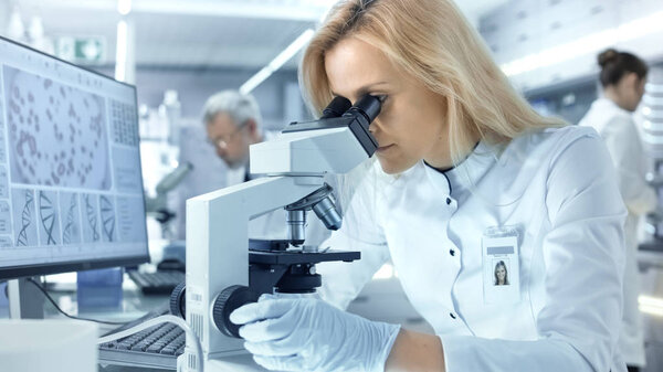 Female Research Scientist Looks at Biological Samples Under Micr