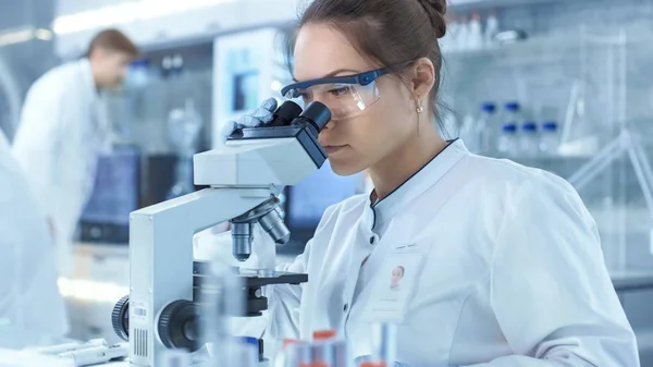 Científicos de investigación médica mirando muestras bajo microscopio . —  Fotos de Stock