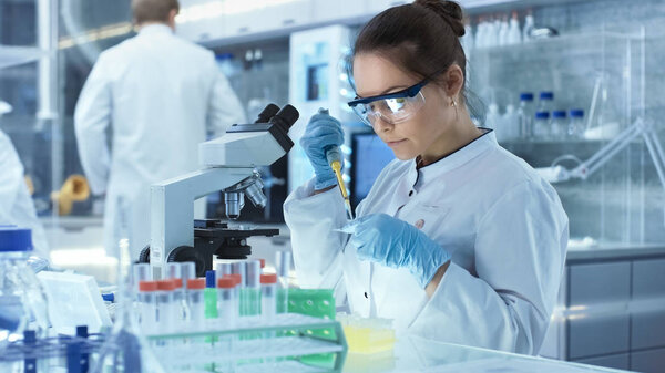 Female Research Scientist Uses Micropipette Filling Test Tubes i