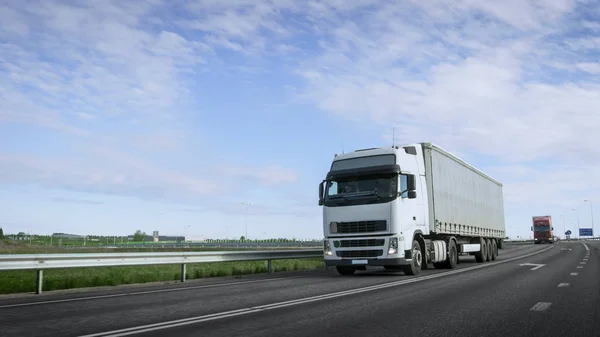 Скоростной белый полугрузовик с грузовым прицепом едет на высокой скорости — стоковое фото