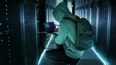 Kukuletalı bir Hacker dizüstü bilgisayar ile sunucu raf bağlanır ve ben çaldı