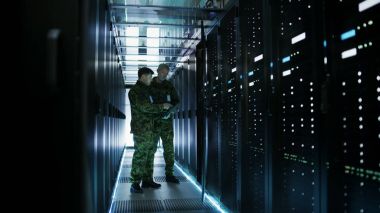 Veri merkezinde iki askeri adam açık Server Rack kabin ile çalışıyor.