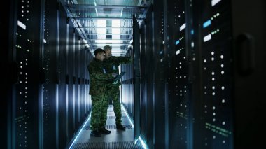 Veri merkezinde iki askeri adam açık Server Rack kabin ile çalışıyor.