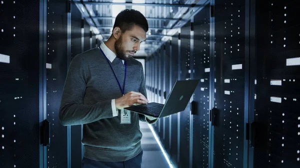 Techniker arbeitet an einem Laptop im großen Rechenzentrum voller Racks — Stockfoto