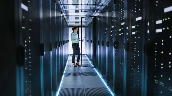 Техник женского сервера стоит рядом с кабинетом в центре обработки данных C — стоковое фото