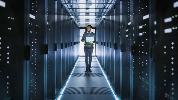 IT Technician Works on Laptop in Big Data Center full of Rack Se