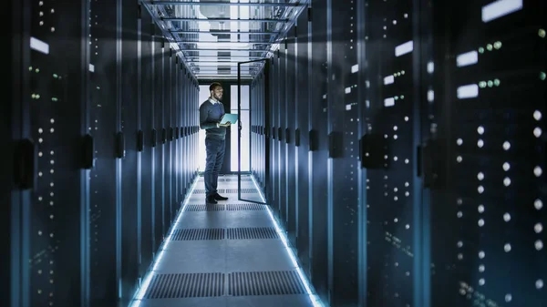 Techniker arbeitet an Laptop in großem Rechenzentrum voller Racks — Stockfoto