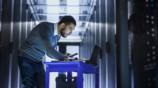 IT Engineer with Tool Cart Working on a Laptop Computer, he Hold