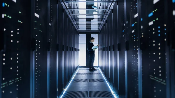 Manliga det ingenjör arbetar på en bärbar dator i slutet av en korridor i en — Stockfoto