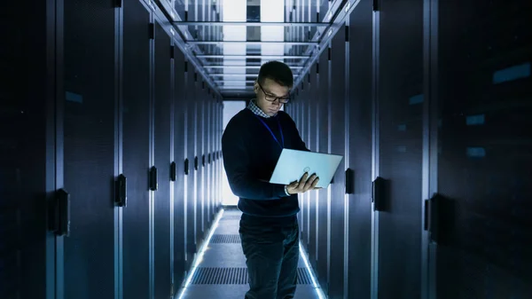 Мужчина IT инженер работает на ноутбуке перед серверным шкафом на — стоковое фото