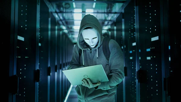 Mittlere Aufnahme eines maskierten Hackers in einem Kapuzenpulli, der in der Mitte steht. — Stockfoto