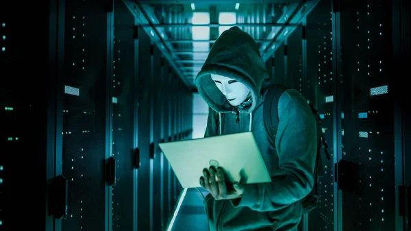 Mittlere Aufnahme eines maskierten Hackers in einem Kapuzenpulli, der in der Mitte steht. — Stockfoto