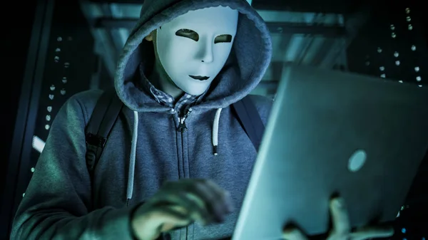 Primer plano de un hacker enmascarado en una sudadera con capucha de pie en el medio — Foto de Stock