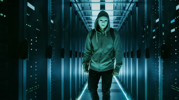 Постріл замасковані хакер в балахон стоїть в центрі даних з — стокове фото