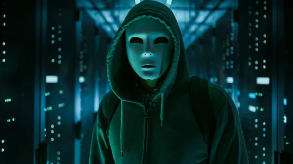 Masked Hacker in a Hoodie Standing in Corporate Data Center with — Stock Photo, Image