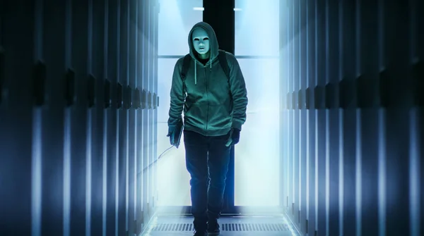 Hacker enmascarado con sudaderas camina a través del centro de datos Corri —  Fotos de Stock