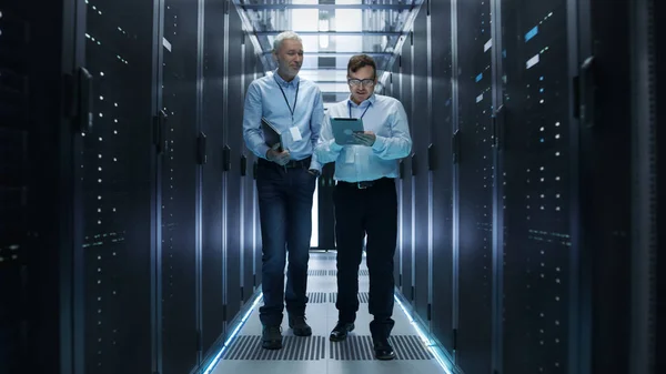 В дата-центре два IT-инженера проходят по рядам серверов R — стоковое фото