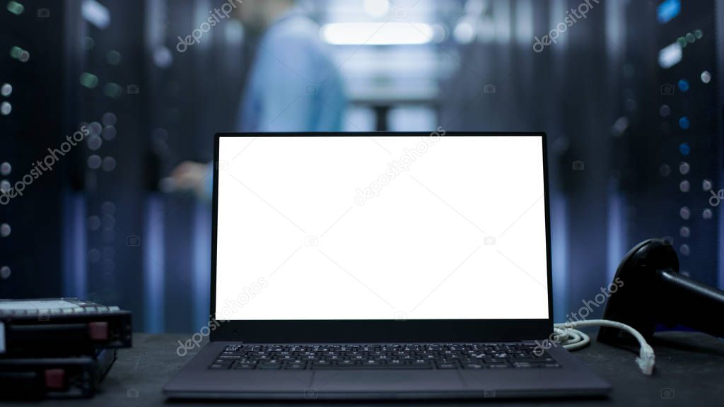 Laptop with White Screen on It Stands on The Table. In the Backg