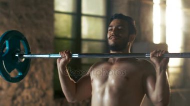 Kaldırma ağır Halter ve işin askeri basın sanayi spor salonu yapılar alıştırmada bir kas gömleksiz adam Close-Up.