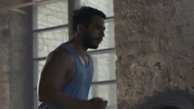 Kolsuz tişörtlü kaslı adam terk edilmiş Sanayi Yapılar içinde çalışır.