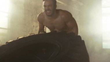 Güçlü kas adam asansörleri / lastik parçası onun vücut geliştirme / Fitness Eğitim çapraz olarak çevirir. O salona ter ve inşaat dışarı içinde terk edilmiş fabrikası Remodeled kaplıdır.