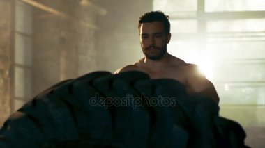 Güçlü kas adam asansörleri / lastik parçası onun vücut geliştirme / Fitness Eğitim çapraz olarak çevirir. O salona ter ve inşaat dışarı içinde terk edilmiş fabrikası Remodeled kaplıdır.