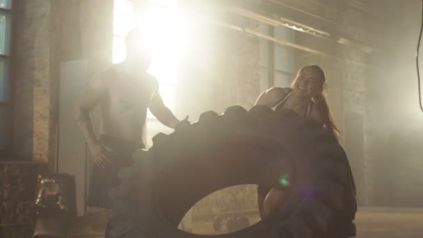 Fit Athletic Woman Lifts Tire Under Supervision of Her Partner / Trainer, as Part of Her Cross Fitness / Bodybuilding Gym Training. Ella le da los cinco altos a su musculoso compañero / entrenador sin camisa . — Vídeos de Stock