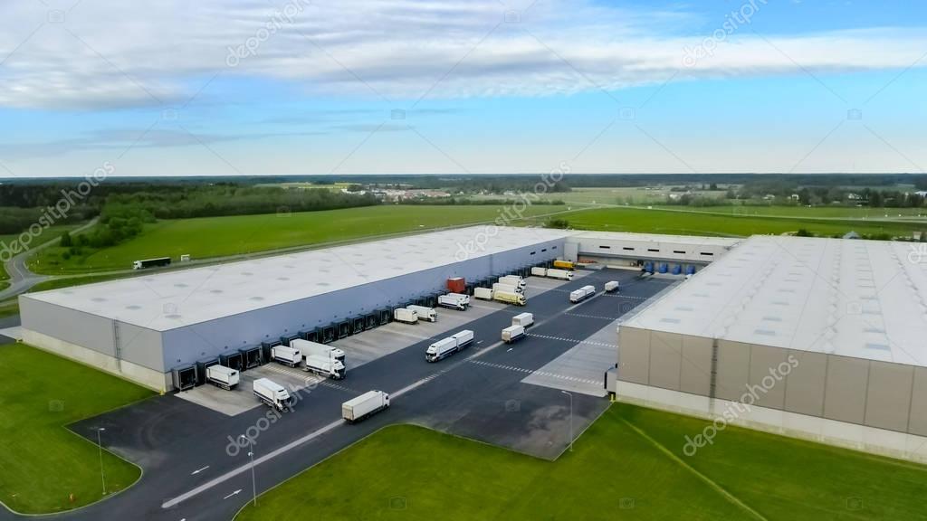 Aerial Shot of Industrial Warehouse/ Storage Building/ Loading Area where Many Trucks Are Loading/ Unloading Merchandise.
