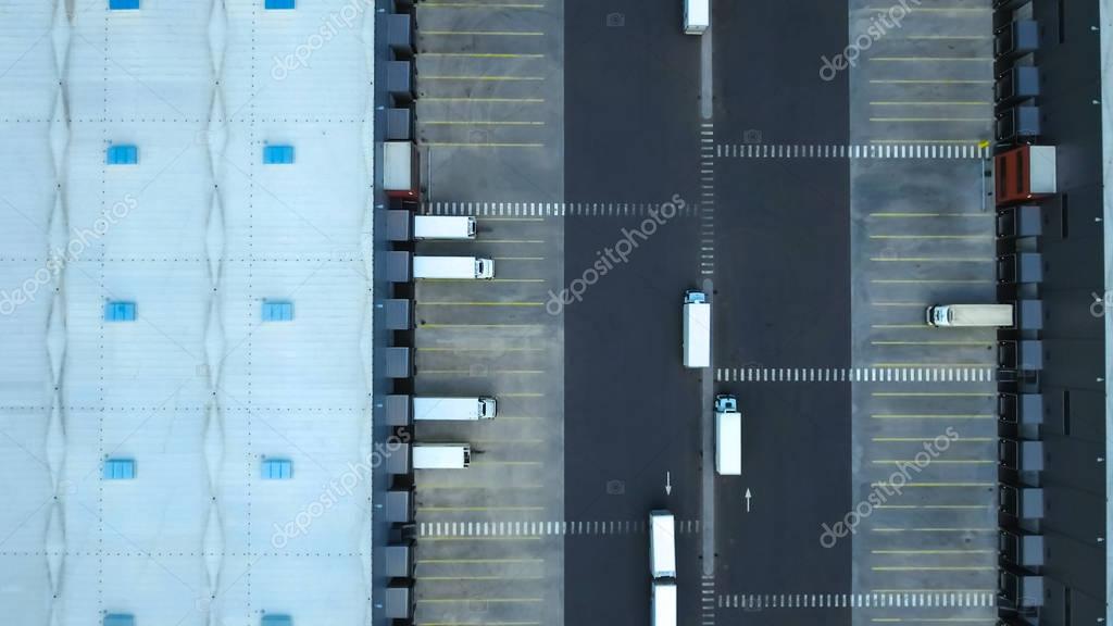 Aerial Shot of Industrial Warehouse/ Storage Building/ Loading Area where Many Trucks Are Loading/ Unloading Merchandise.