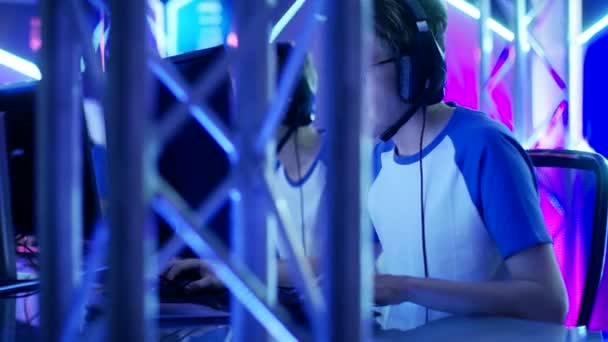 Team von Jungen und Mädchen, die an einem Multiplayer-Videospielturnier teilnehmen. Sie benutzen Headsets und sprechen in Mikrofone. Internetcafé / Spielarena ist in Neonlicht getaucht. — Stockvideo