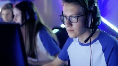 Profesyonel çocuk oyun oynar esports turnuva tarihinde Video oyununda / Internet Cafe. Gözlük ve kulaklık takıyor ve mikrofona konuşur.