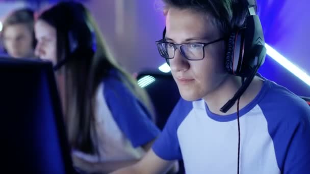 Juguetes profesionales de Boy Gamer en videojuegos en un torneo de eSports / café de Internet. Lleva gafas y auriculares y habla en el micrófono . — Vídeos de Stock