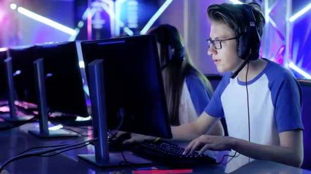 Team professioneller E-Sport-Spieler, die Videospiele auf einem Cyber-Games-Turnier spielen. Mädchen und Jungen haben Kopfhörer auf, Arena ist mit Neonlicht beleuchtet. — Stockvideo