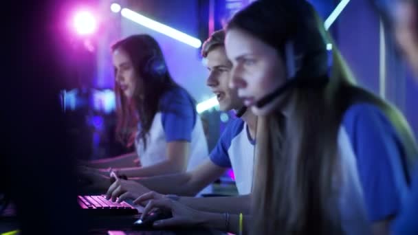 Profundidad de tiro de campo del equipo de jugadores adolescentes que juegan en un videojuego multijugador para PC en un torneo de eSport. Hablan en micrófonos. Momento de juego emocional . — Vídeos de Stock