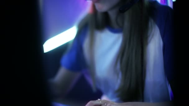 Hermosa chica jugador profesional juega en los juegos cibernéticos, es eSport Cyber Games Tournament / Internet Café. Ella tiene sus auriculares y como líder de equipo comanda maniobras estratégicas en el micrófono . — Vídeos de Stock
