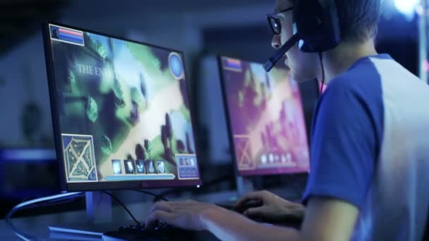 Professional Gamer Plays in MMORPG/ Strategy Video Game on His Computer. He's Participating in Online Cyber Games Tournament, Plays at Home, or in Internet Cafe. He Wears Glasses and Gaming Headsets. — Stock Video