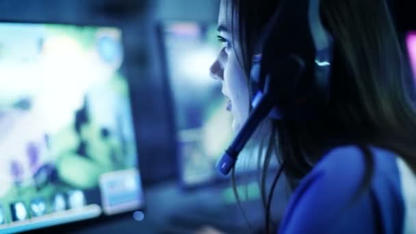 Jogadores profissionais jogam em MMORPG / jogo de estratégia em seu computador. Ela está participando do Torneio de Jogos Cibernéticos Online, ou no Internet Cafe. Ela usa fones de ouvido para jogos . — Vídeo de Stock