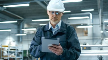 Kask içinde kıdemli mühendis bir facto bir tablet bilgisayar kullanıyor
