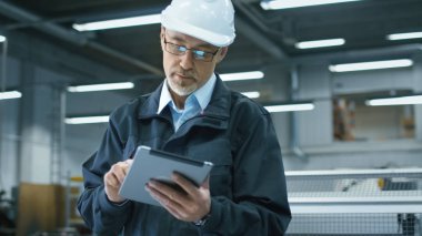 Kask içinde kıdemli mühendis bir facto bir tablet bilgisayar kullanıyor