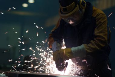 Ağır sanayi işçisi bir fabrikada metali üzerinde çalışıyor bir bir
