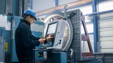 Factory worker is programming a CNC milling machine with a table clipart