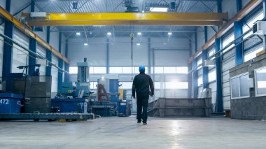 Fabrika işçisi kask içinde endüstriyel facil yürüyor