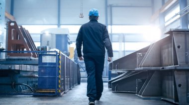 Fabrika işçisi kask içinde endüstriyel facil yürüyor