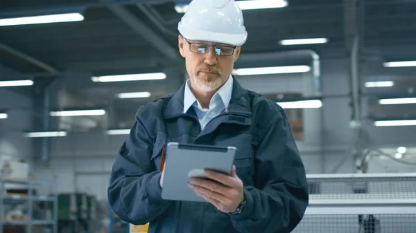 Senior ingenieur in veiligheidshelm is het gebruik van een tablet-pc in een facto — Stockfoto