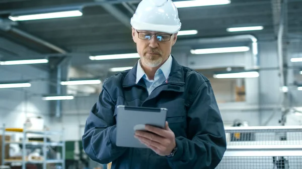 Senior ingenieur in veiligheidshelm is het gebruik van een tablet-pc in een facto — Stockfoto