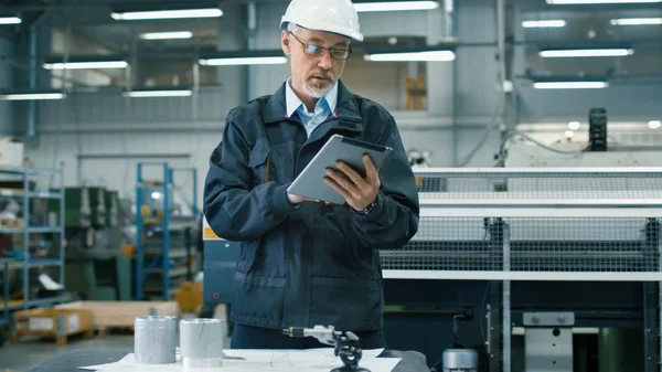 Senior engineer in hardhat is using a tablet computer in a facto — Stock Photo, Image