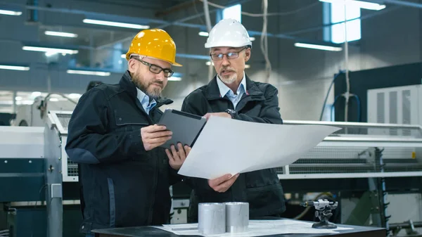 Deux ingénieurs discutent d'un plan tout en vérifiant les informations sur — Photo