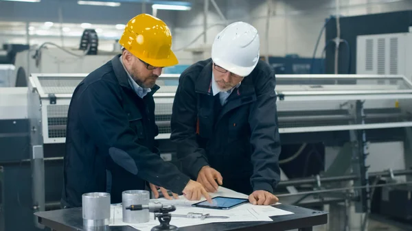 Twee ingenieurs bespreken een blauwdruk terwijl het controleren van de informatie op — Stockfoto